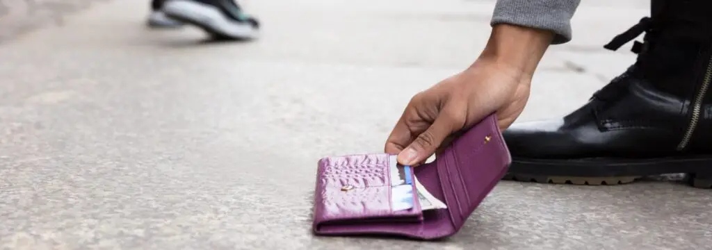 a person picking up a purple lost wallet on the ground