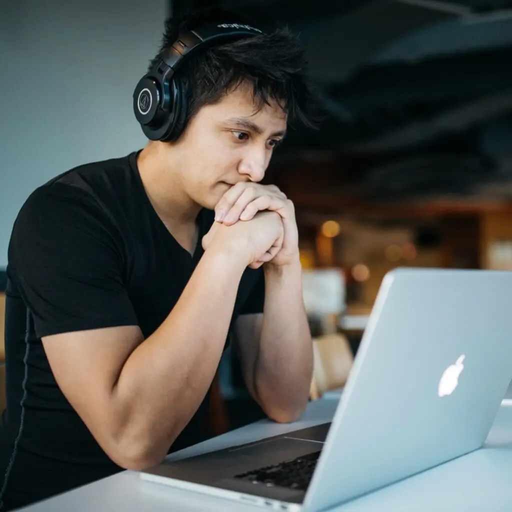 Man wearing headphones looking at laptop computer