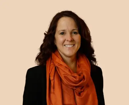 woman smiling wearing black top with orange scarf