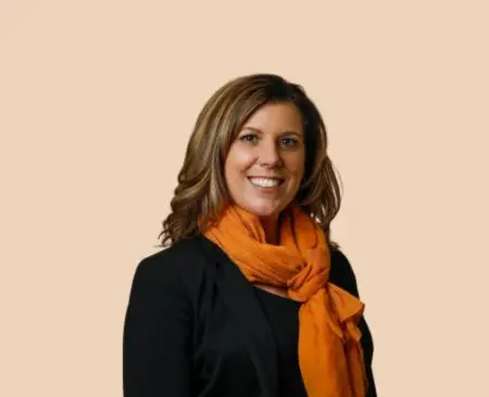 smiling woman with brown hair in a black blouse with an orange scarf