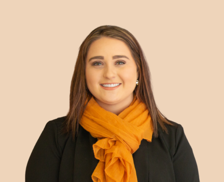 Lindsey Walker smiling wearing a black blouse with orange scarf
